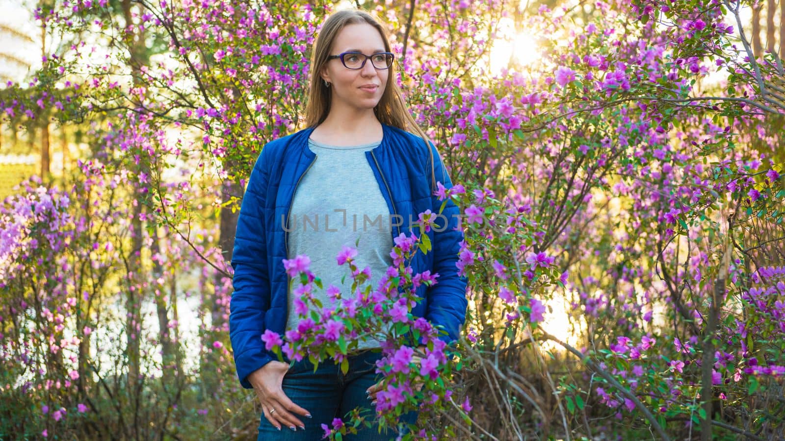 Woman travelling in Altai mountains on spring beautiful booming pink Rhododendron flowers background