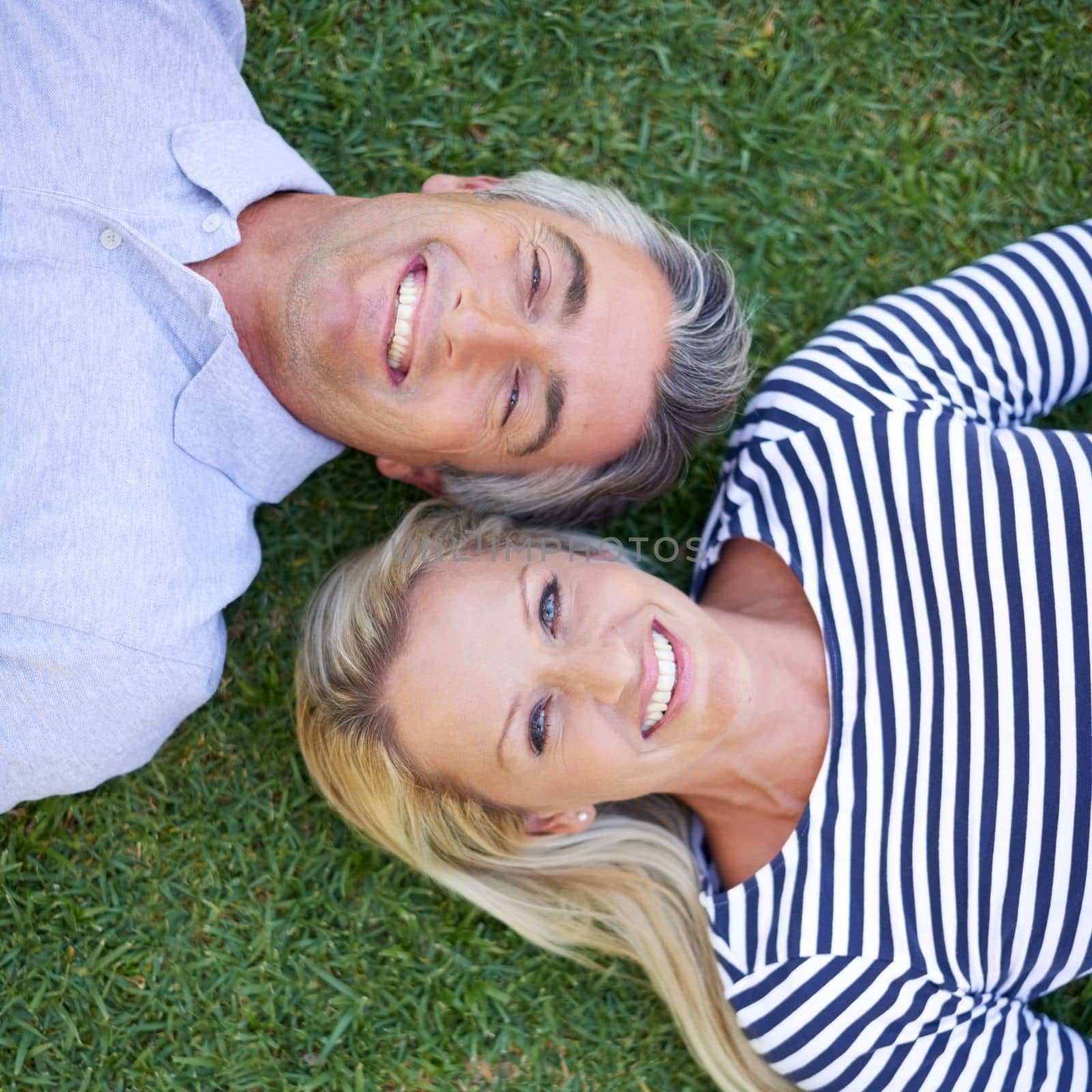 You wont find us indoors on this beautiful day. High angle portrait of a mature couple lying in the park. by YuriArcurs