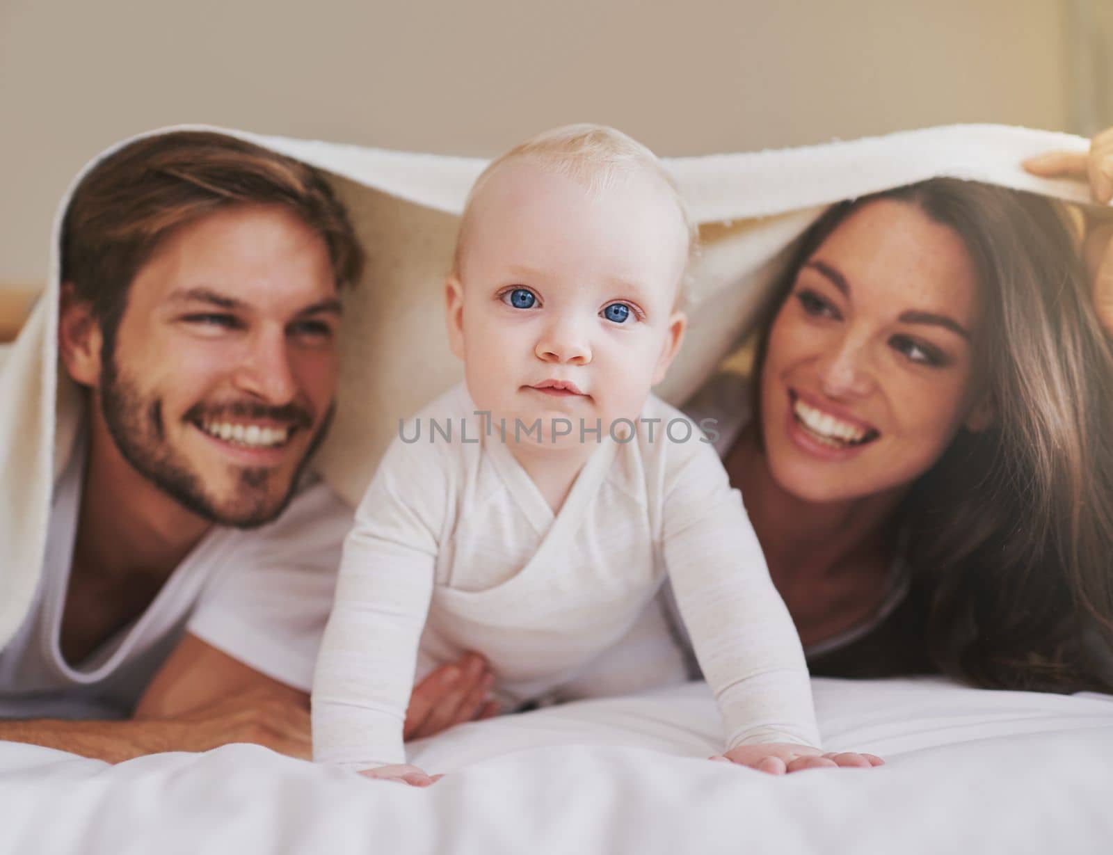 One happy family. a young couple and their baby daughter in the bedroom. by YuriArcurs