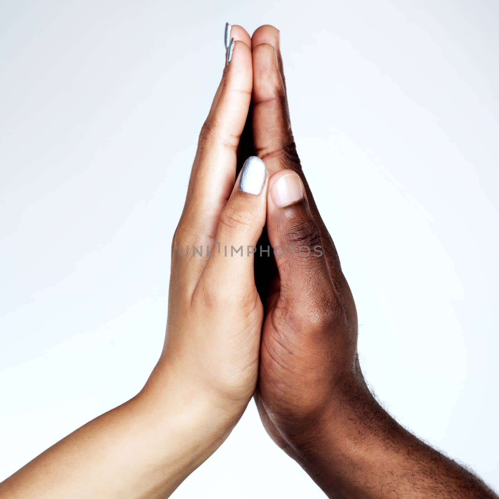 Feel the energy. Studio shot of two unrecognizable people holding their hands together against a grey background. by YuriArcurs