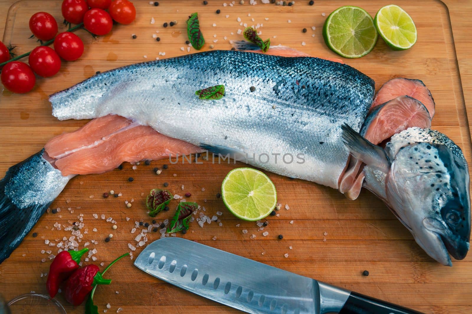 Fresh raw salmon fish on the kitchen wooden board with spices and lime
