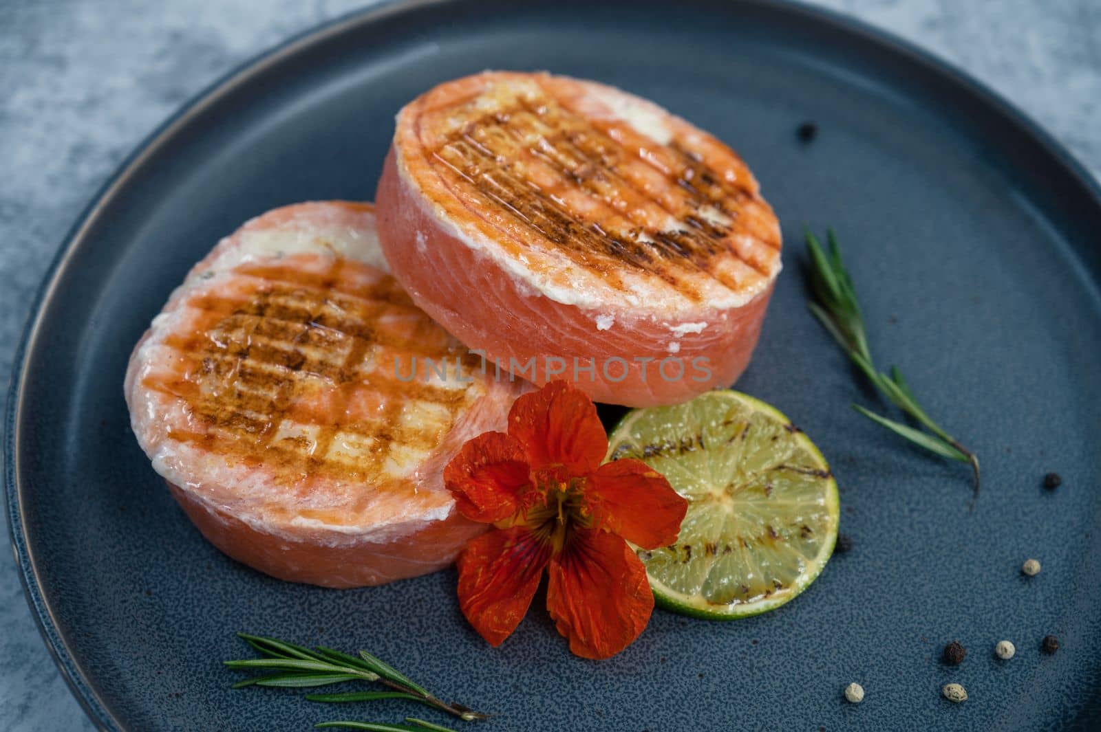 Grilled salmon roll with mozzarella. Decorated with greens lime and edible flower
