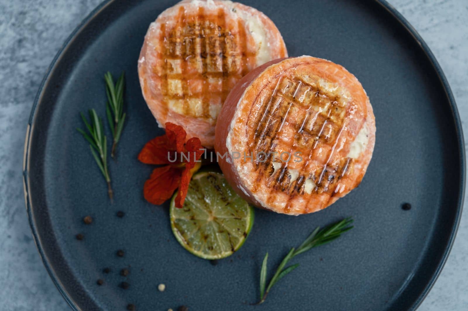 Grilled salmon roll with mozzarella. Decorated with greens lime and edible flower
