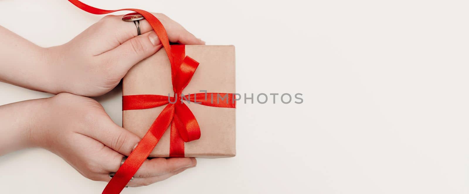 Hand red gift. Women's hands hold a present for christmas or valentine's day. Isolated on white background. View from above by Matiunina
