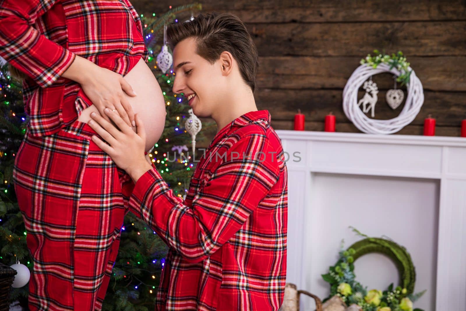 A man kneels in front of a woman and touches her pregnant belly. by fotodrobik