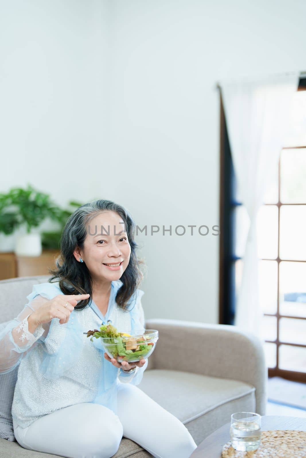 Portrait of an elderly Asian woman taking care of her health by eating salad. by Manastrong