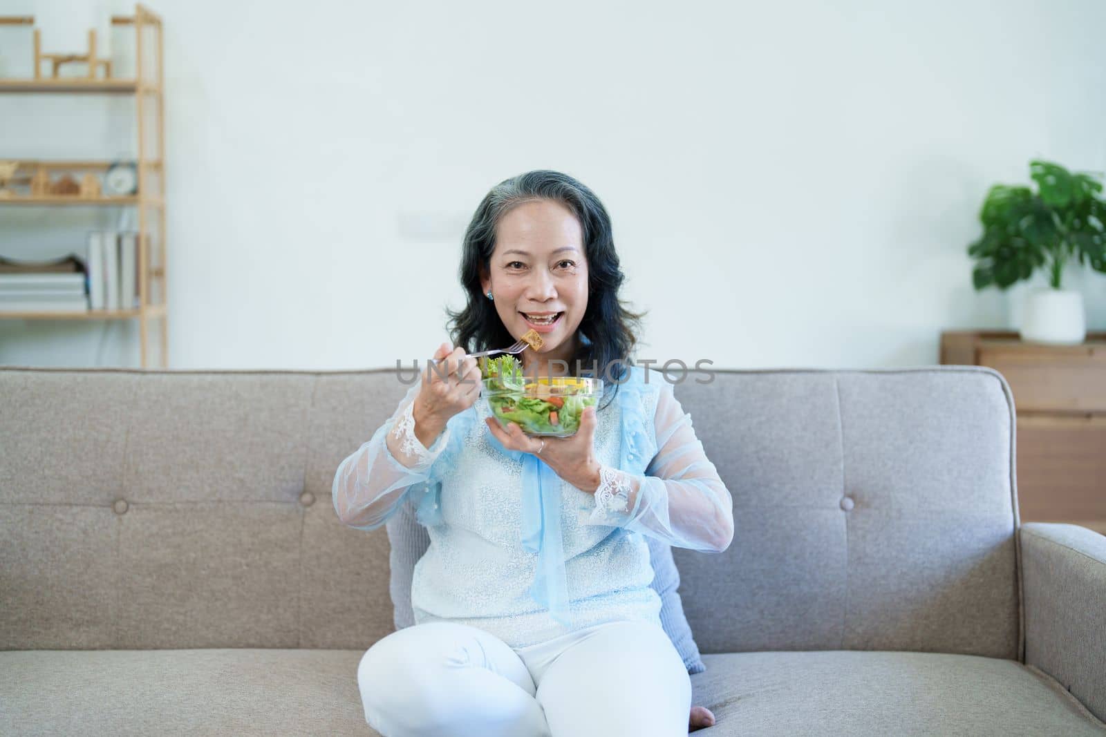 Portrait of an elderly Asian woman taking care of her health by eating salad