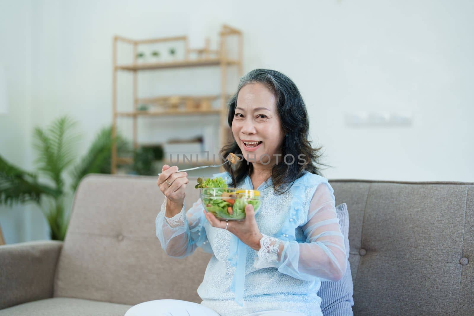 Portrait of an elderly Asian woman taking care of her health by eating salad. by Manastrong