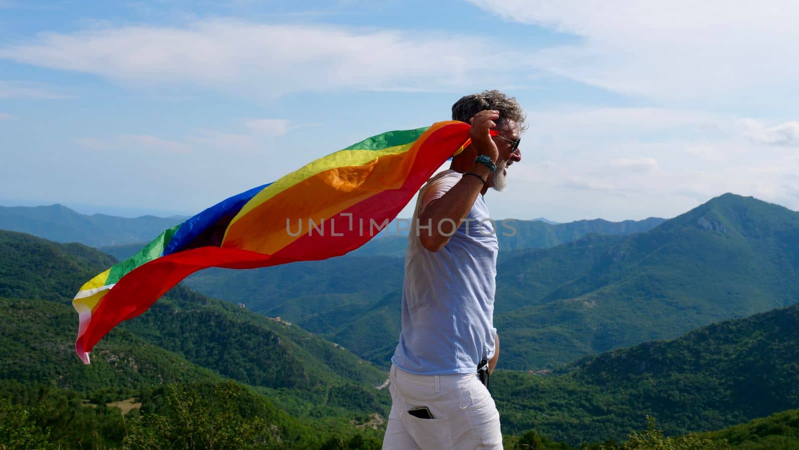 Bisexual, gay, old man, male, transsexual walk with LGBTQIA flag, rainbow peace in pride mounts on the nature on a day and celebrate Bisexuality Day or National Coming Out Day