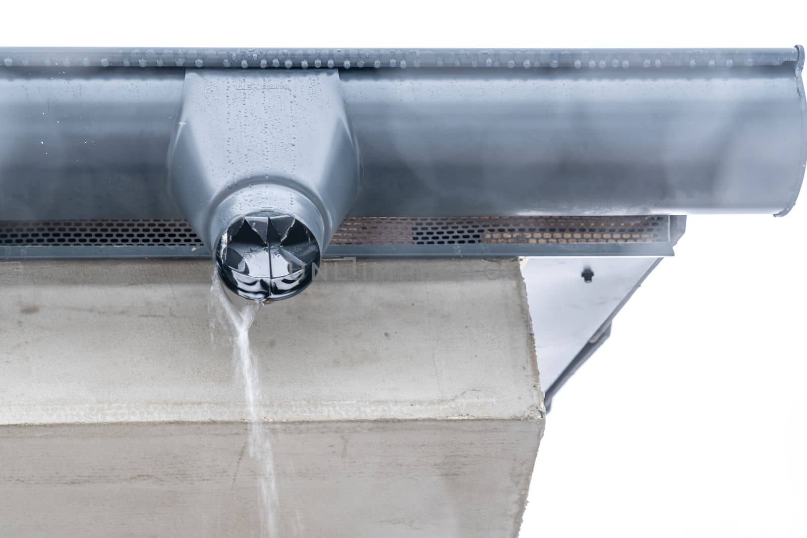 gutter with flowing rainwater on the roof of the building.
