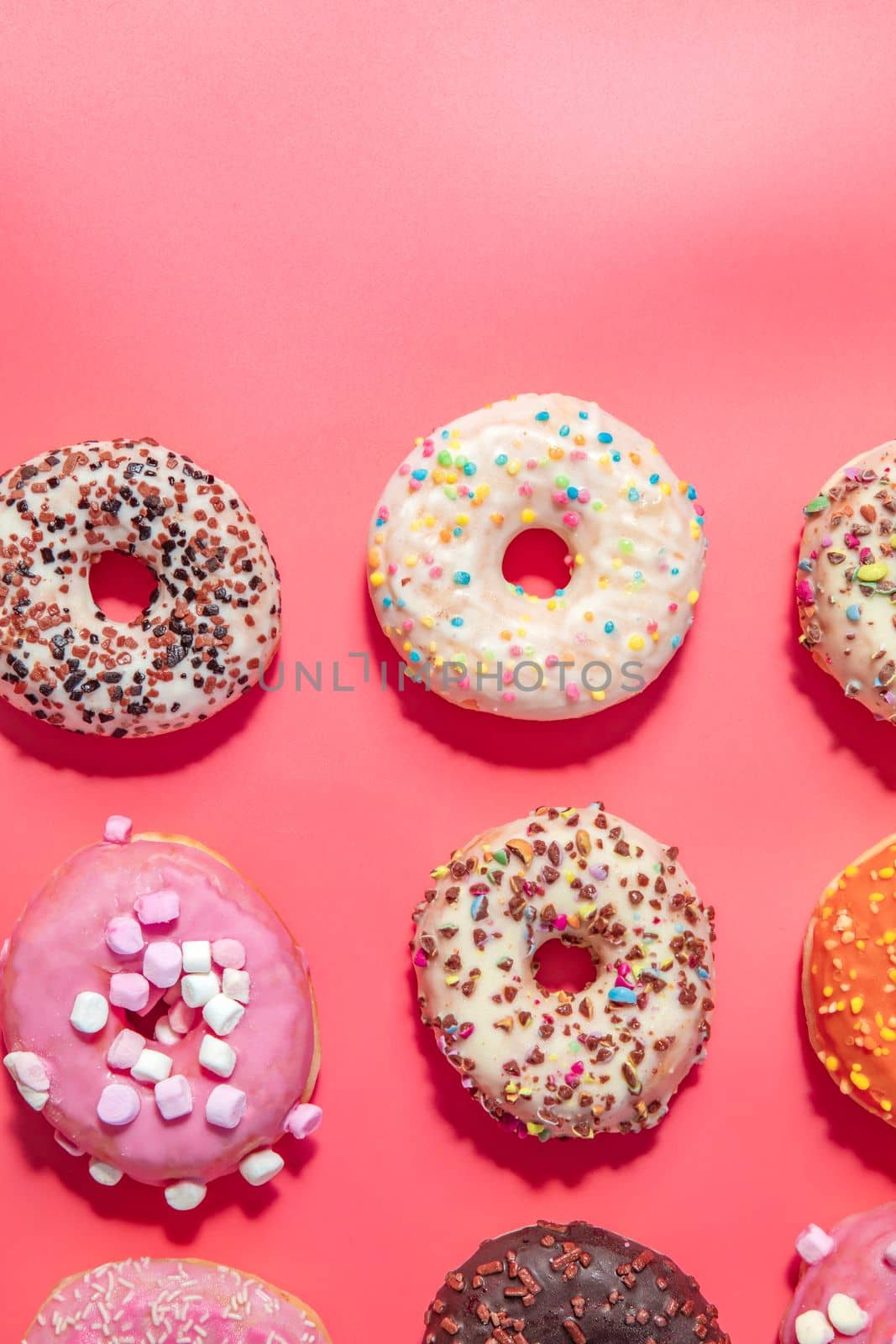 Donuts with icing on pastel pink background. Sweet donuts. top view assorted with various chocolate glazed and sprinkles, sugar sweets concept candy