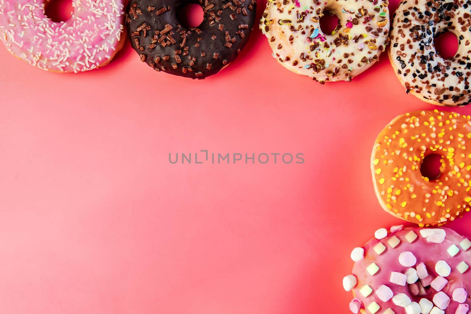 Donuts with icing on pastel pink background. Sweet donuts. top view assorted with various chocolate glazed and sprinkles, sugar sweets concept candy