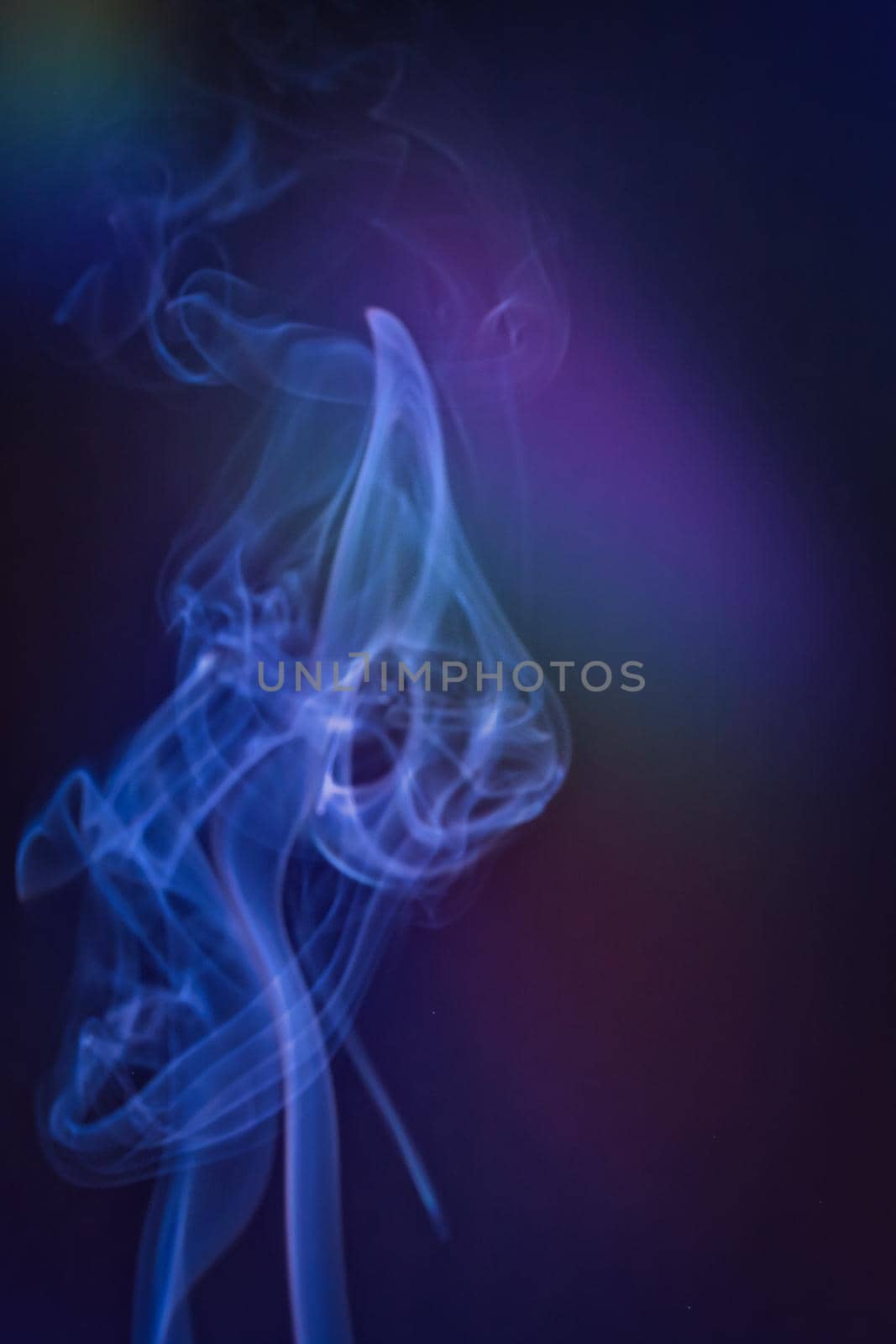 A vertical shot of smoke in colorfull backlight with a blue note