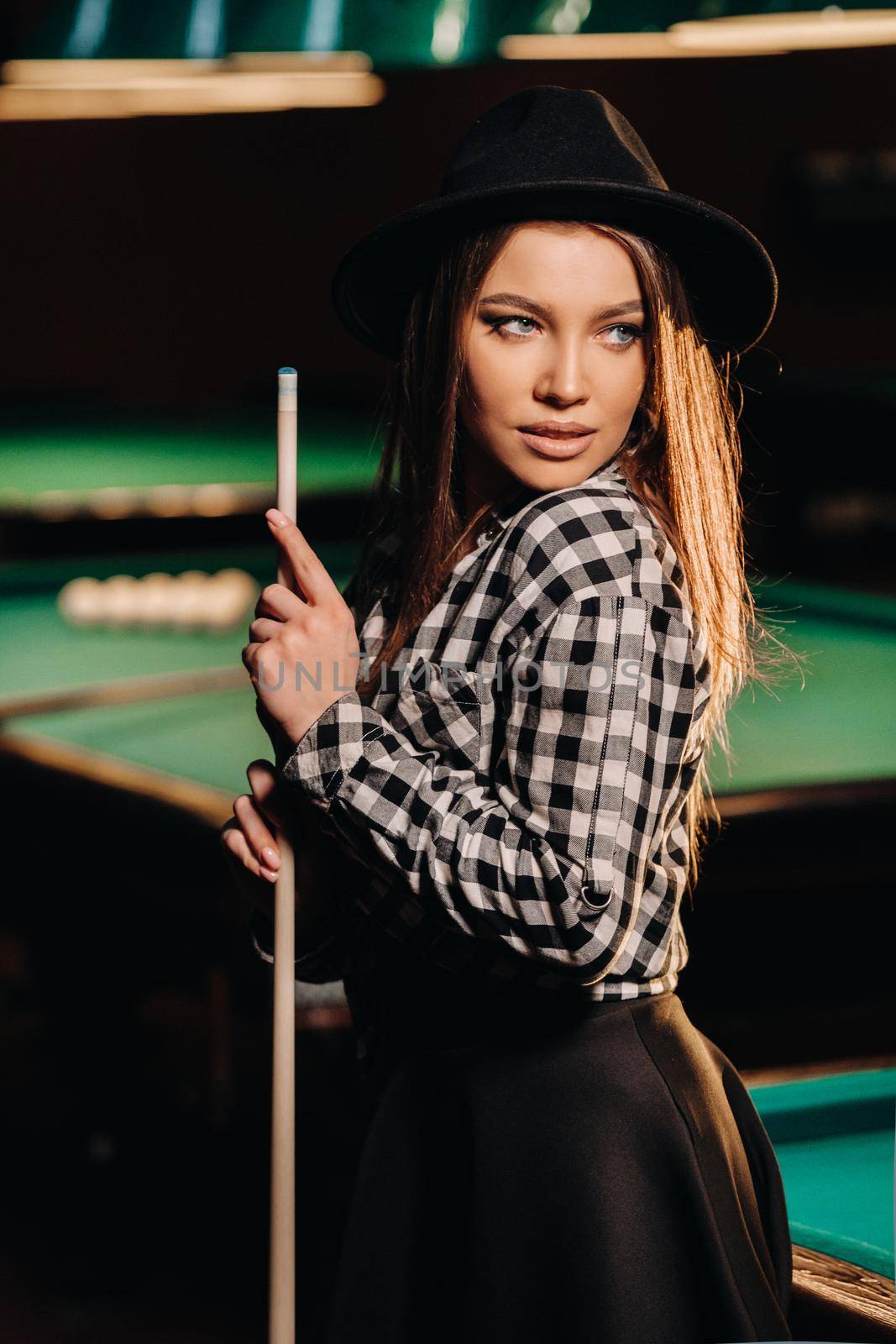 A girl in a hat in a billiard club with a cue in her hands.billiards Game by Lobachad