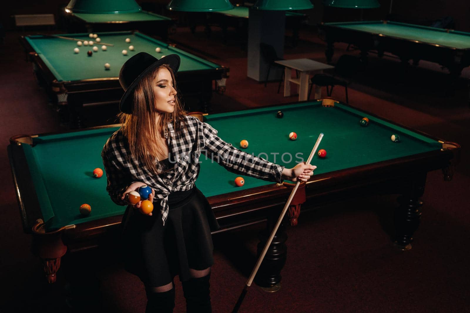 A girl in a hat in a billiard club with a cue in her hands.billiards Game by Lobachad