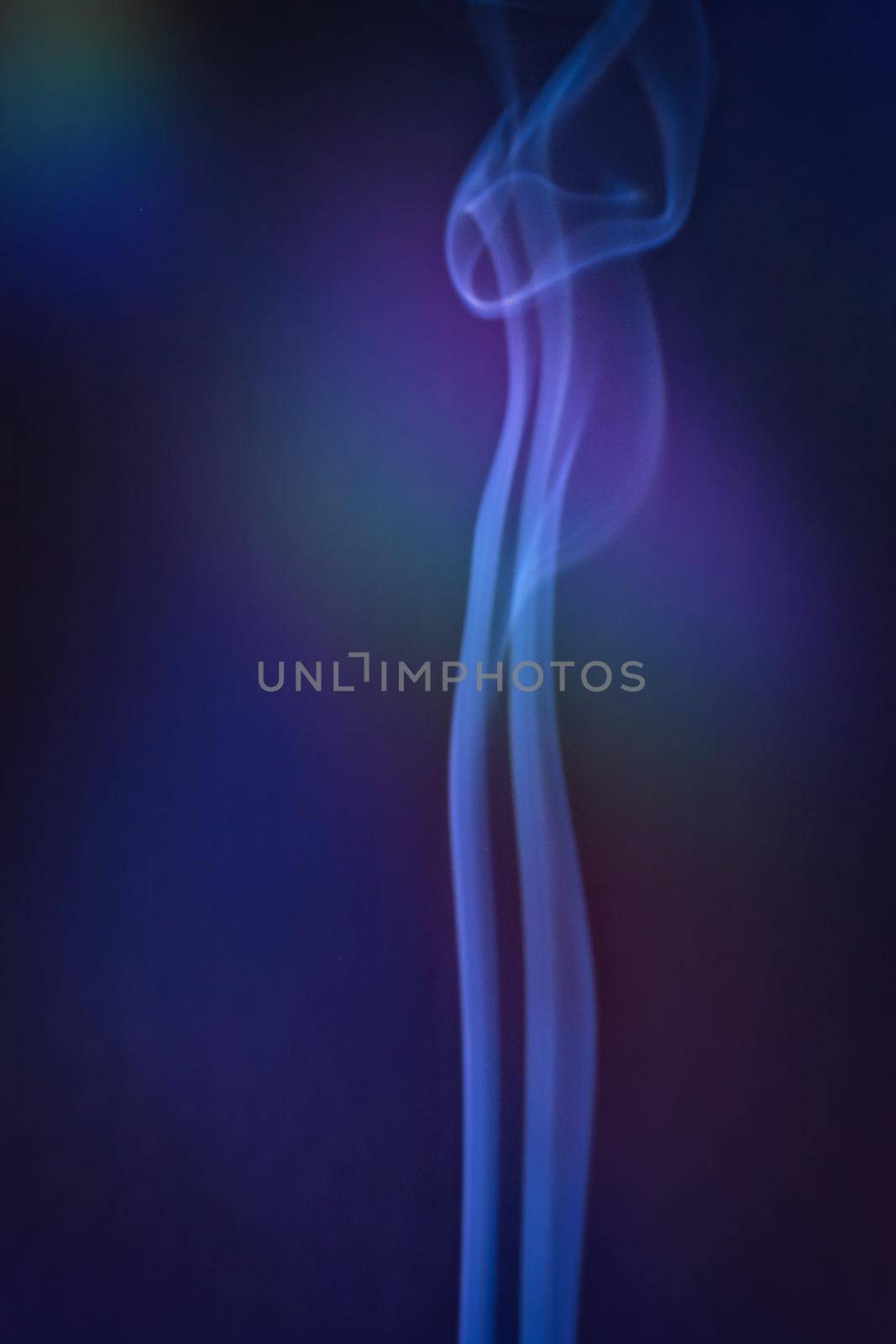 A vertical shot of smoke in colorfull backlight with a blue note