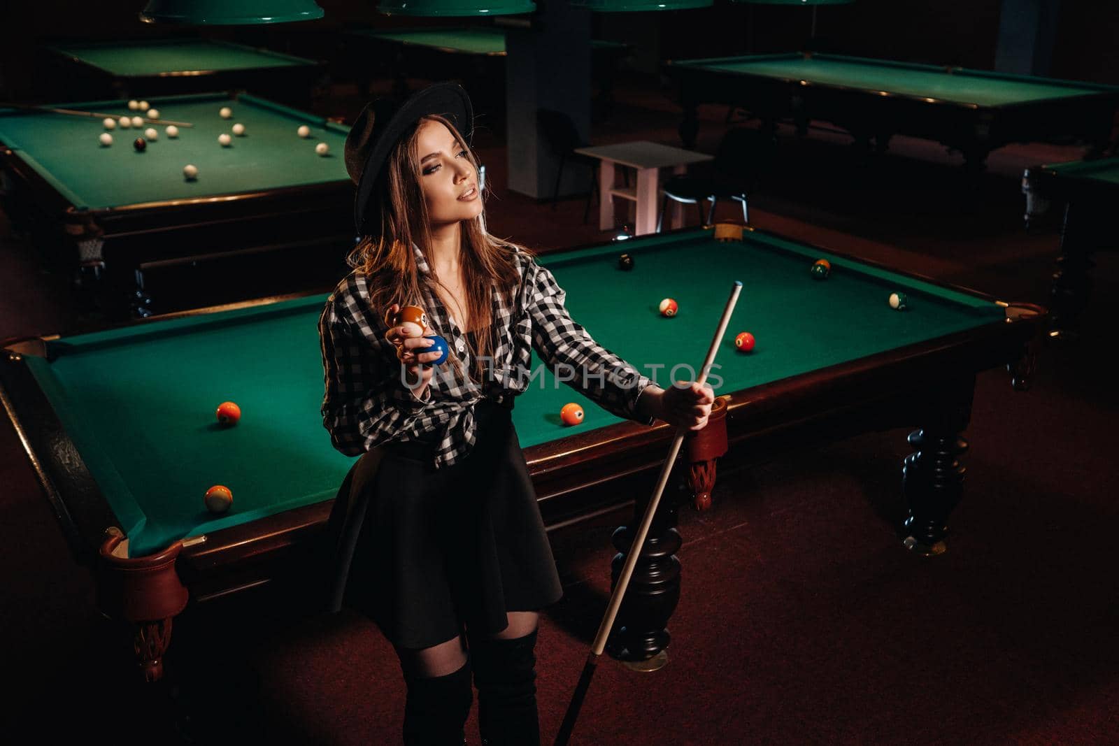 A girl in a hat in a billiard club with a cue in her hands.billiards Game.