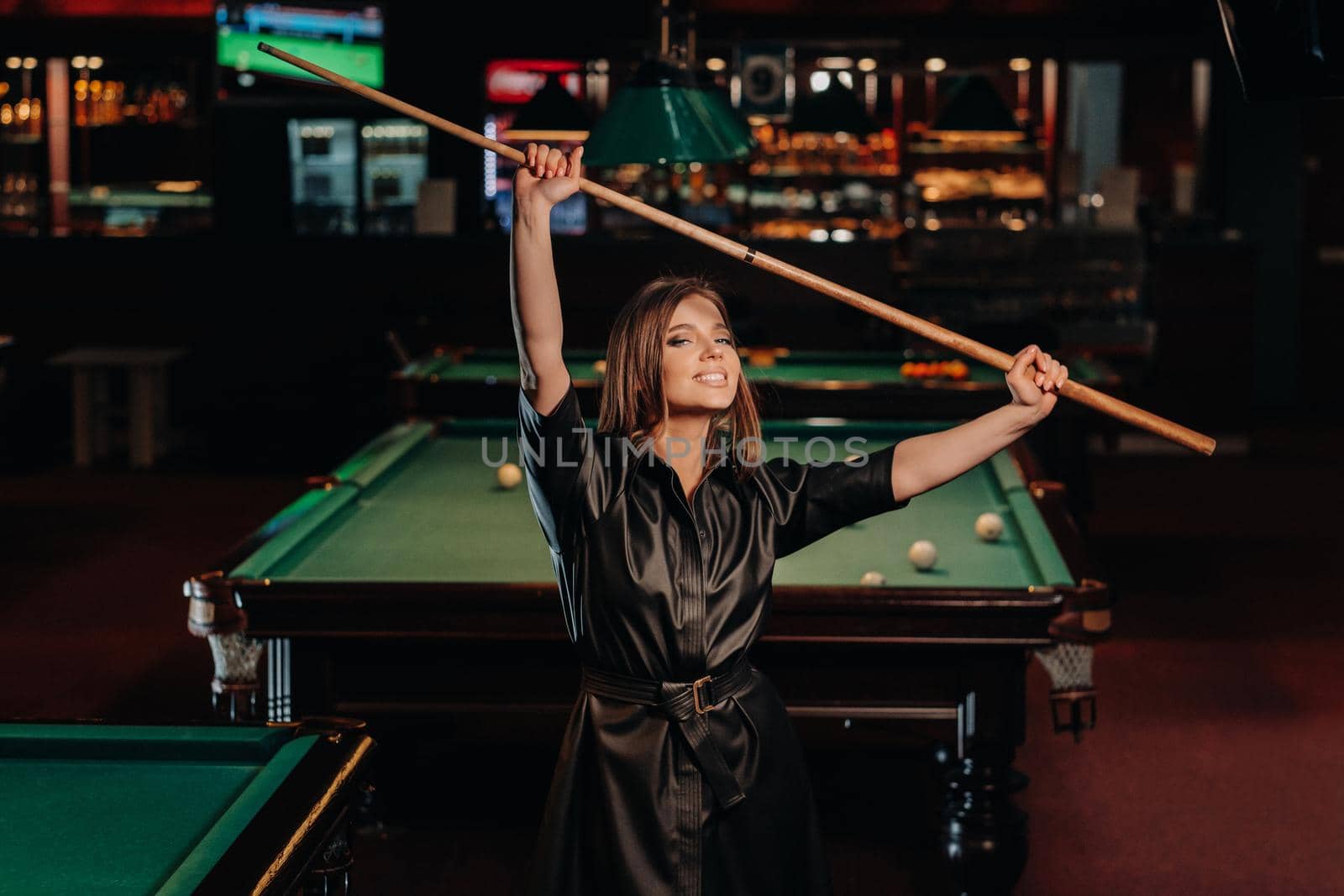 A girl with a cue in her hands is standing in a billiard club.Russian billiards.