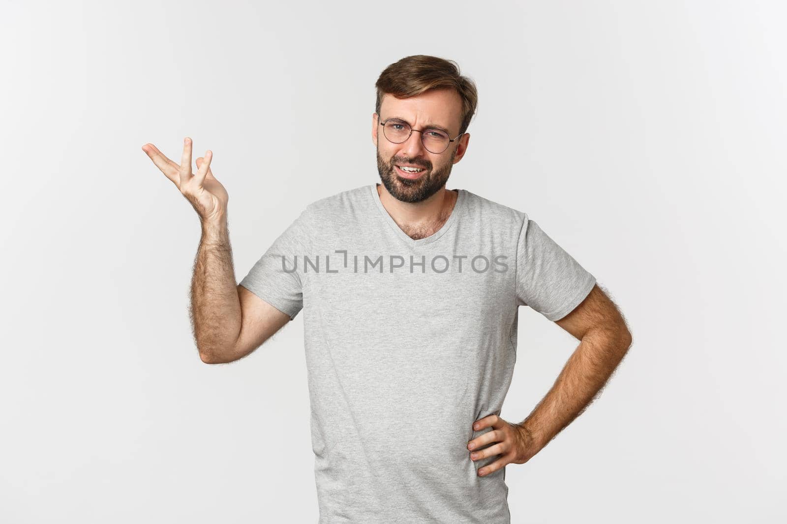 Portrait of handsome adult man looking confused, raising hand up and looking perplexed, standing over white background.