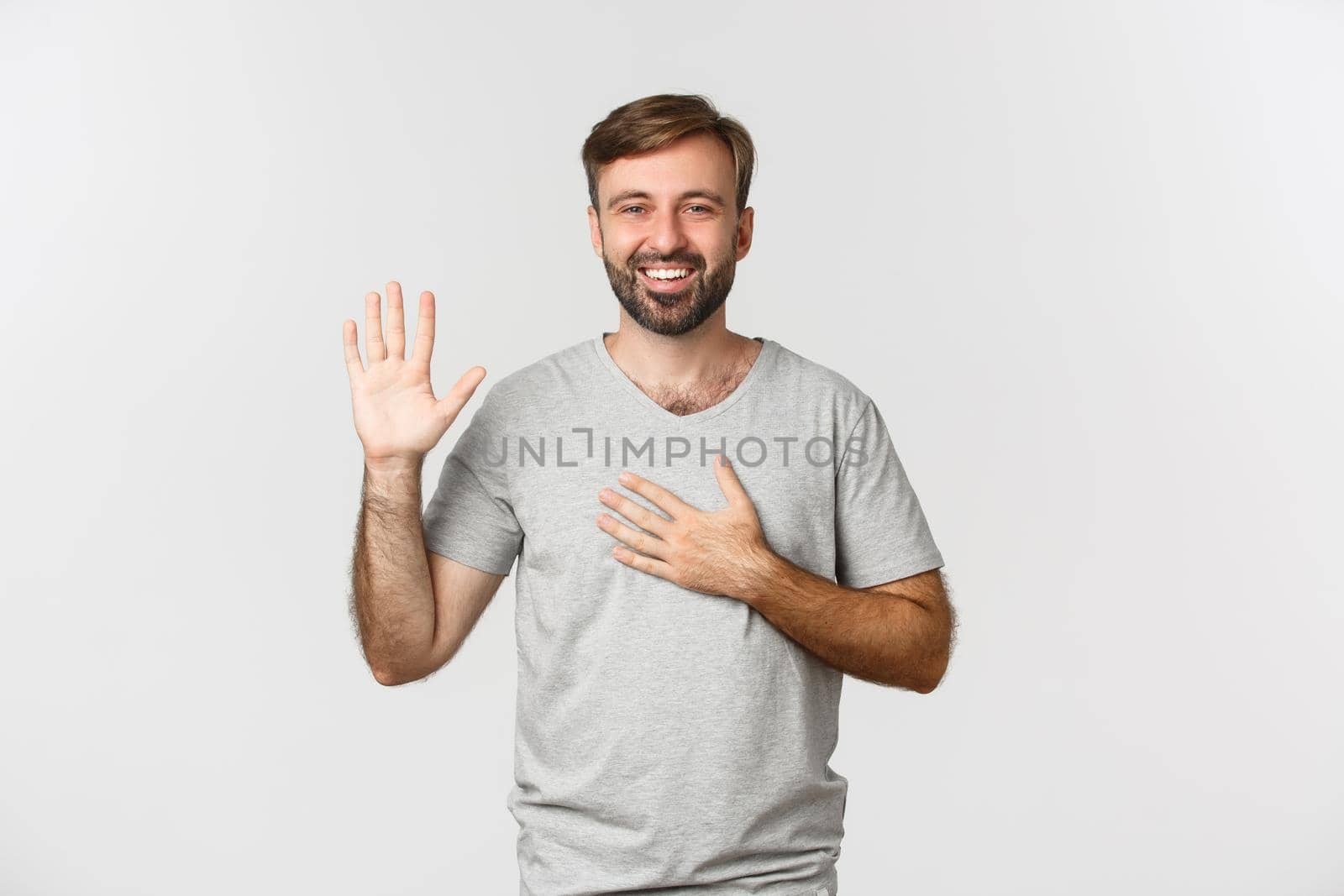 Portrait of sincere handsome guy with beard, making promise, swearing or giving oath, standing over white background.