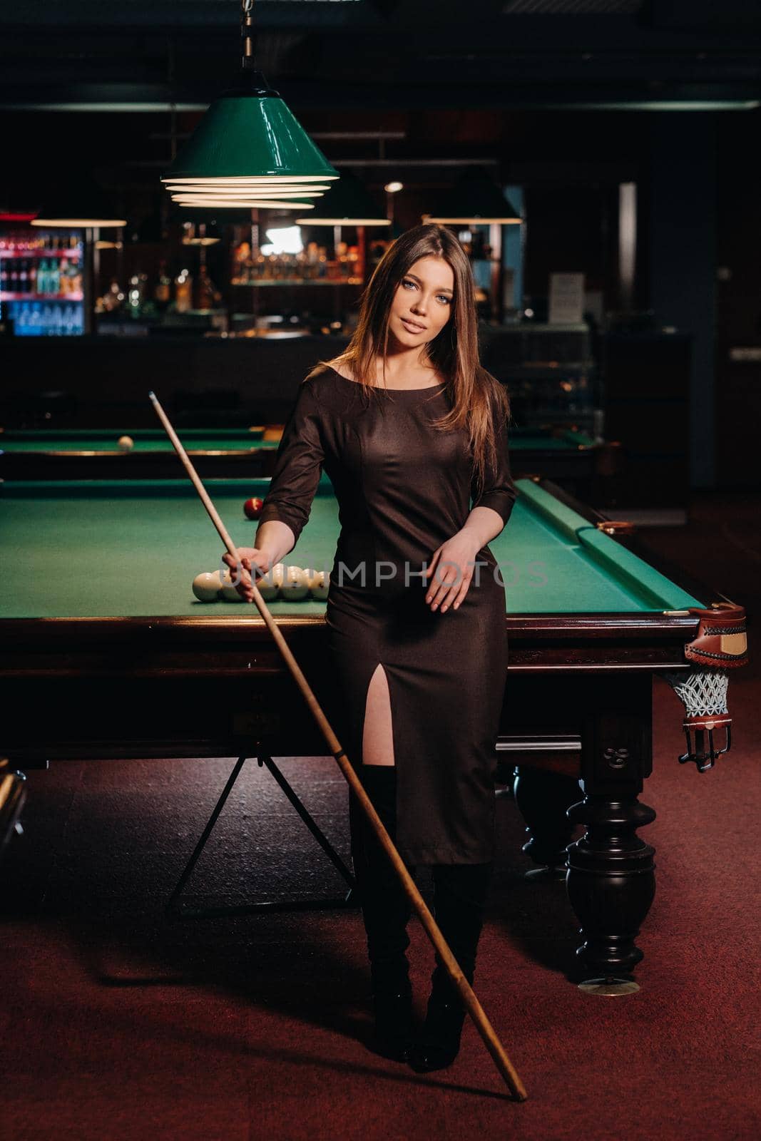 A girl in a hat in a billiard club with a cue in her hands.Pool Game by Lobachad