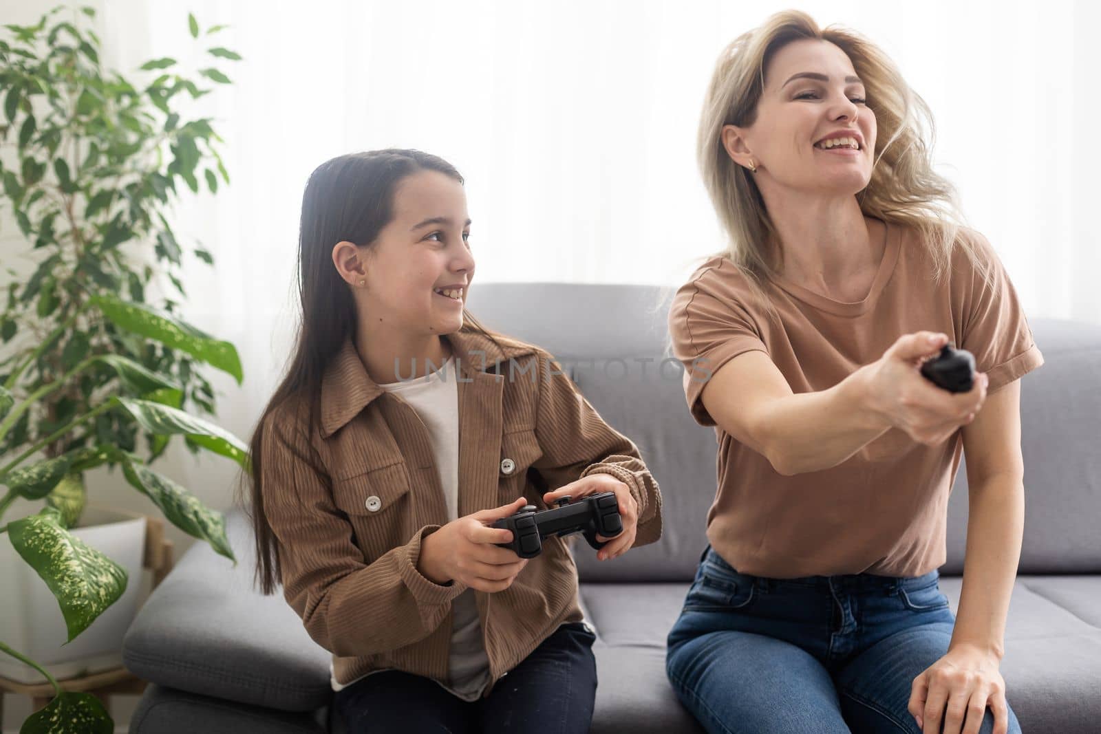 Photo of domestic funny blond lady mom daughter sitting comfy couch hold joystick playing video games stay home safety quarantine spend weekend together best friends living room indoors