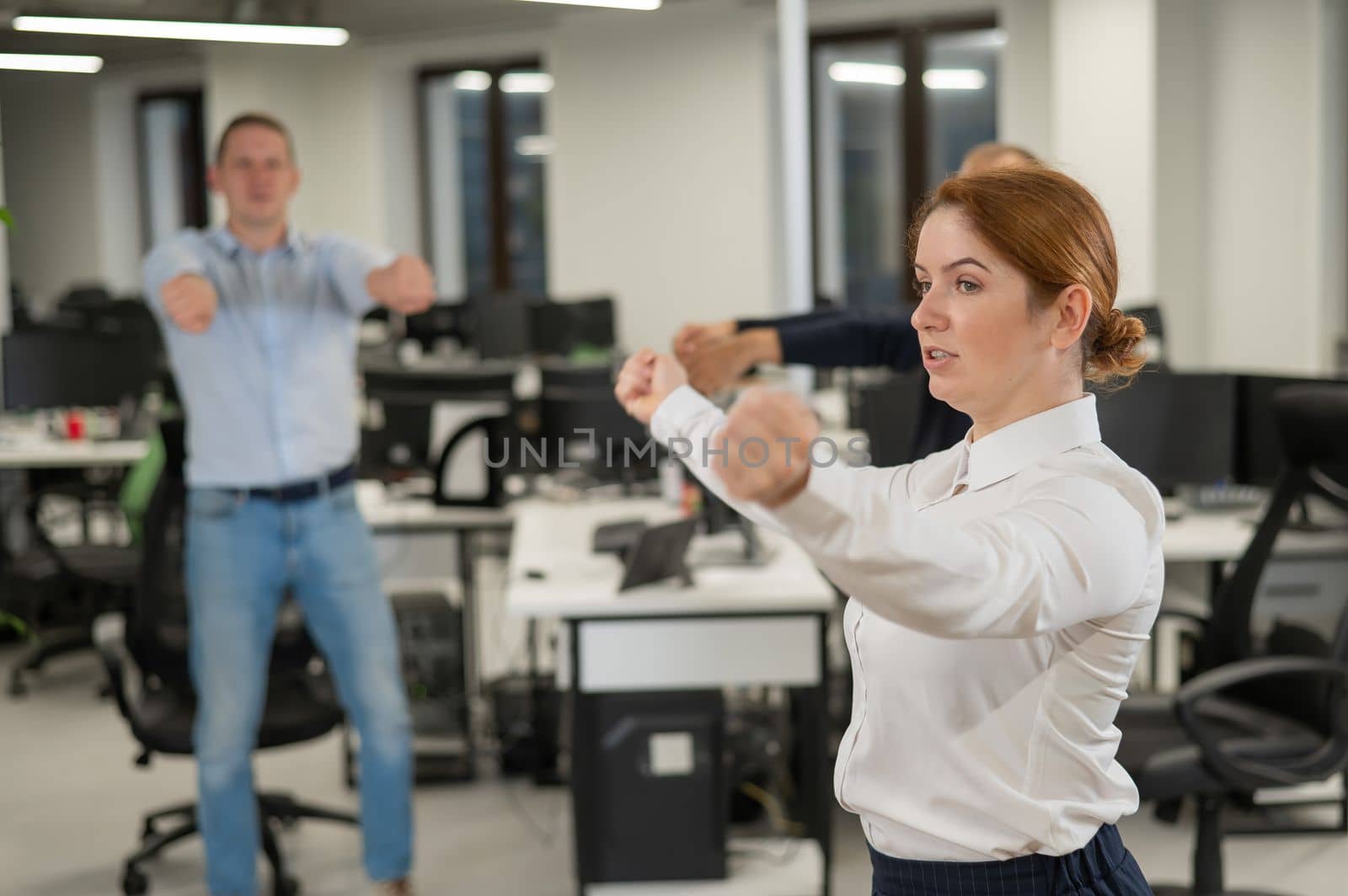 Three office workers warm up during a break. Employees do fitness exercises at the workplace. by mrwed54