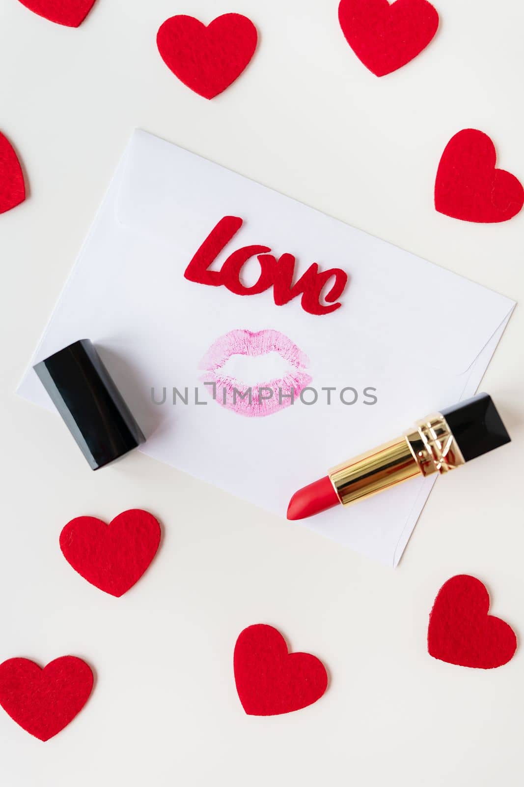 A white envelope with a lip print of red lipstick on a background of small red hearts. February 14 Valentine's Day concept. by sfinks