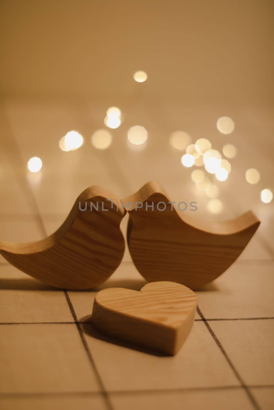 two wooden birds and heart made by bokeh lights background. Valentines day, Easter, Wedding card with wooden figures of birds, home decor.