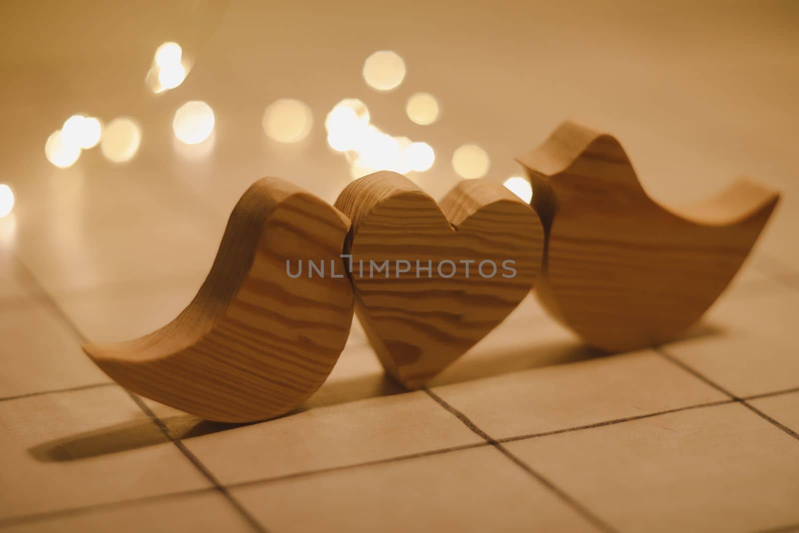 two wooden birds and heart made by bokeh lights background. Valentines day, Easter, Wedding card with wooden figures of birds, home decor.