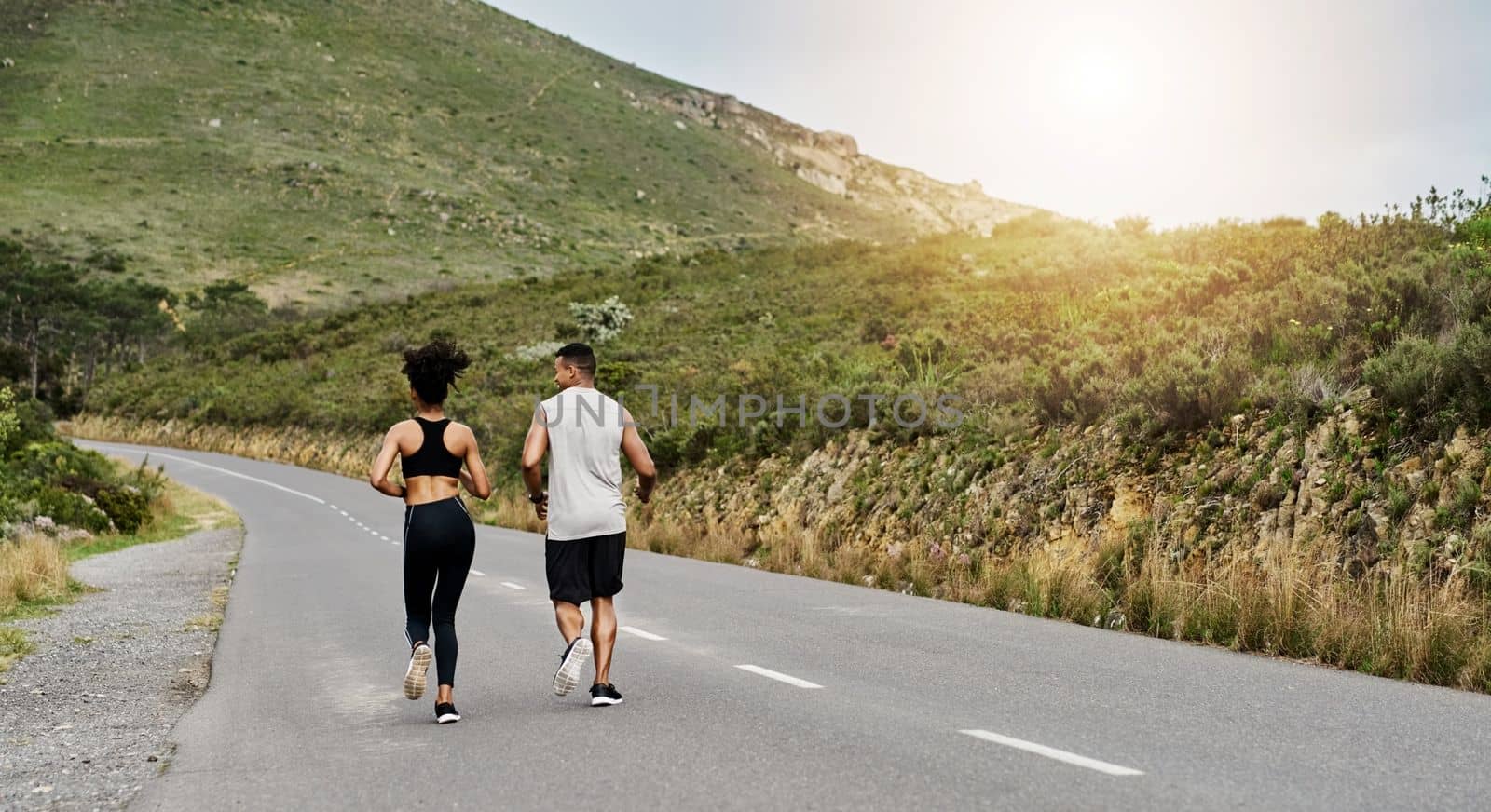 Leading a physically active lifestyle together. Rearview shot of a sporty young couple exercising together outdoors. by YuriArcurs