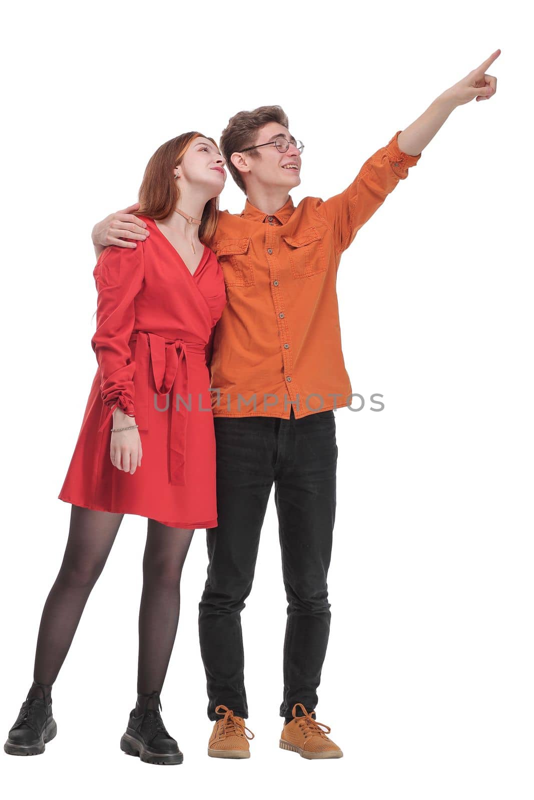 Young cute couple embracing and pointing on white background and looking away
