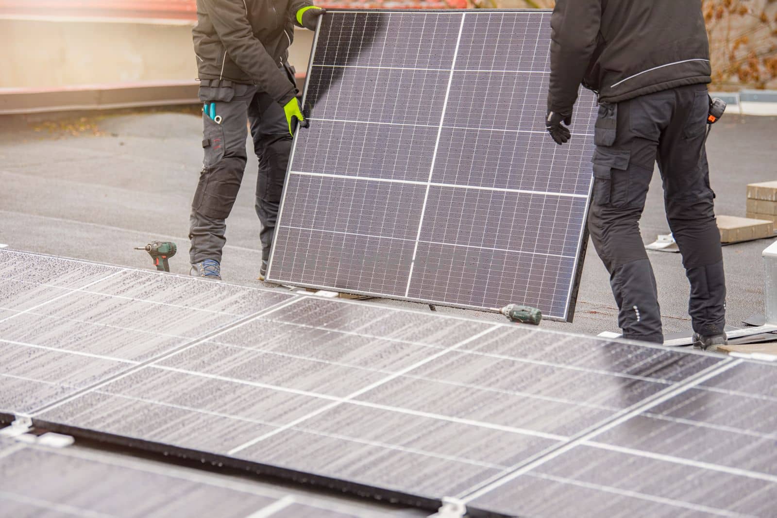 The process of installing solar panels. Solar panel installers work on the roof. Installers carry solar panel module to installation site, green and renewable energy concept by SERSOL