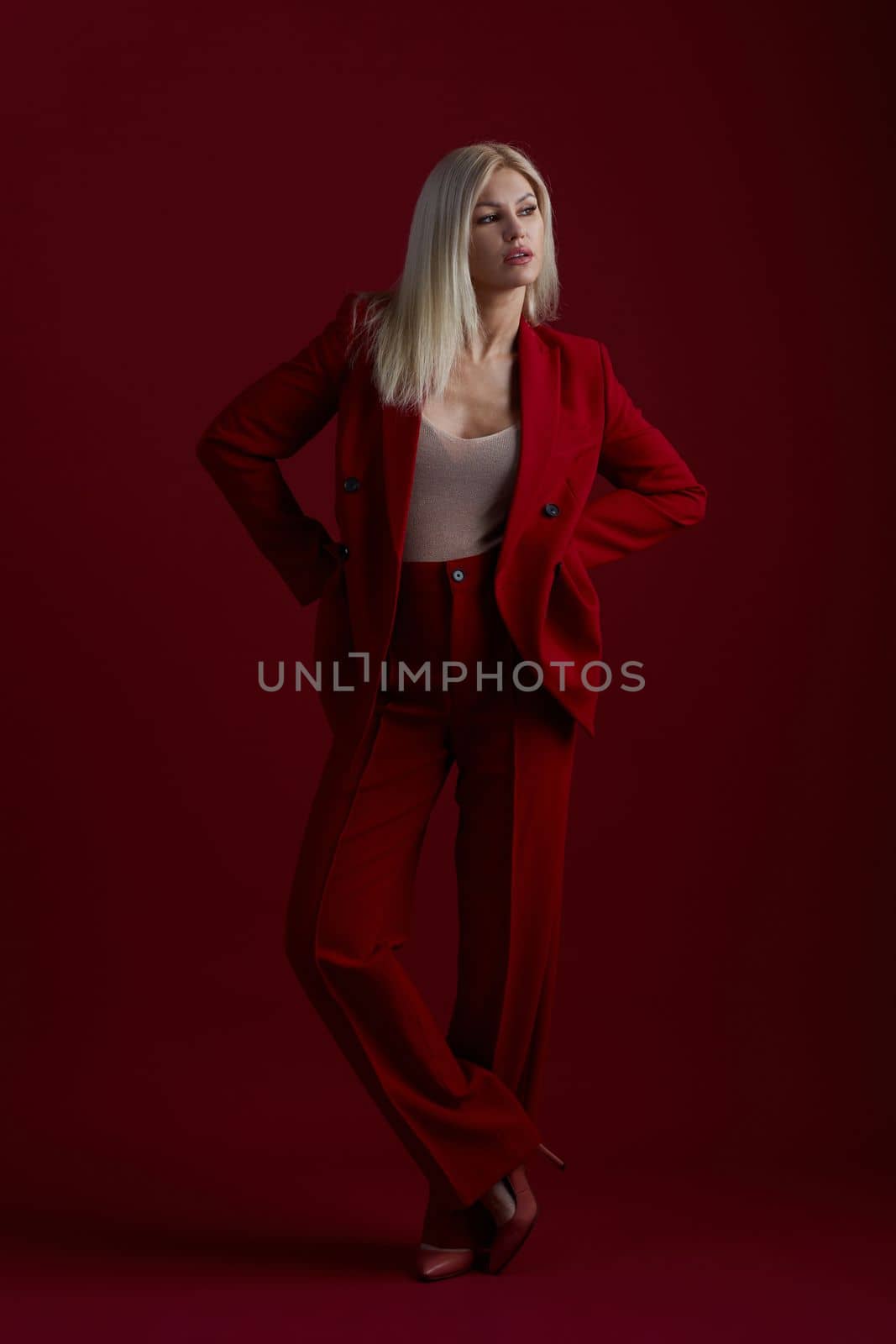 Portrait of a blonde woman in red dress on a red background