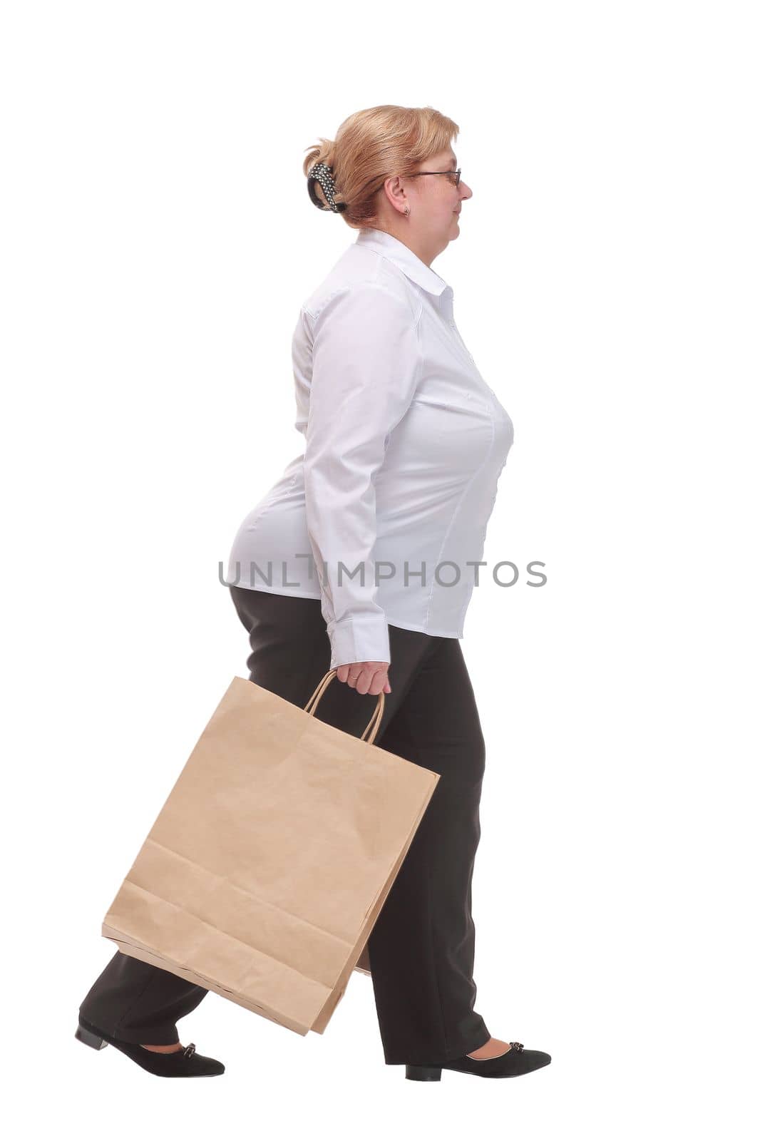 Side view full length portrait of a middle age woman walking with shopping bags by asdf