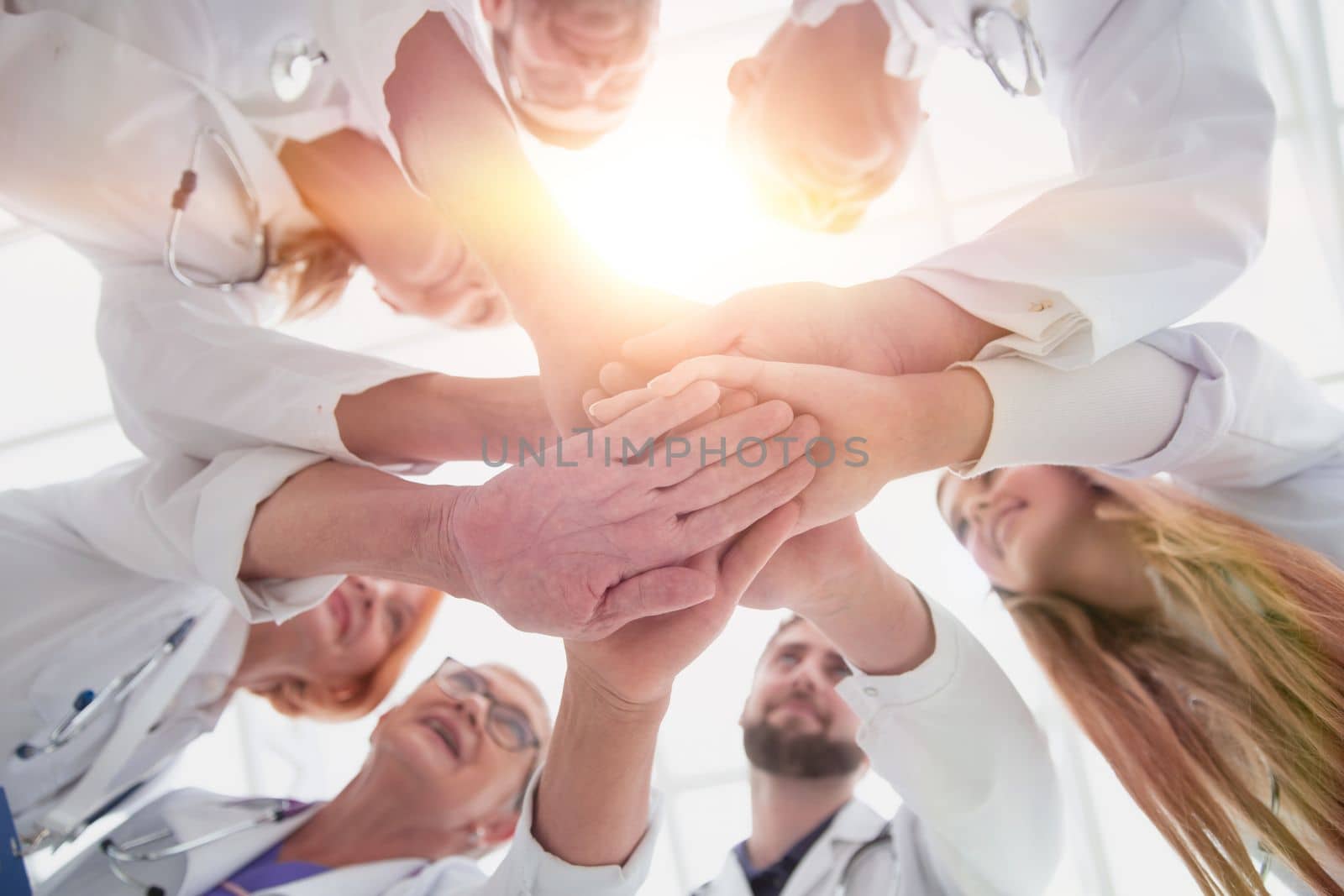 close up. group of different doctors putting their hands together by asdf