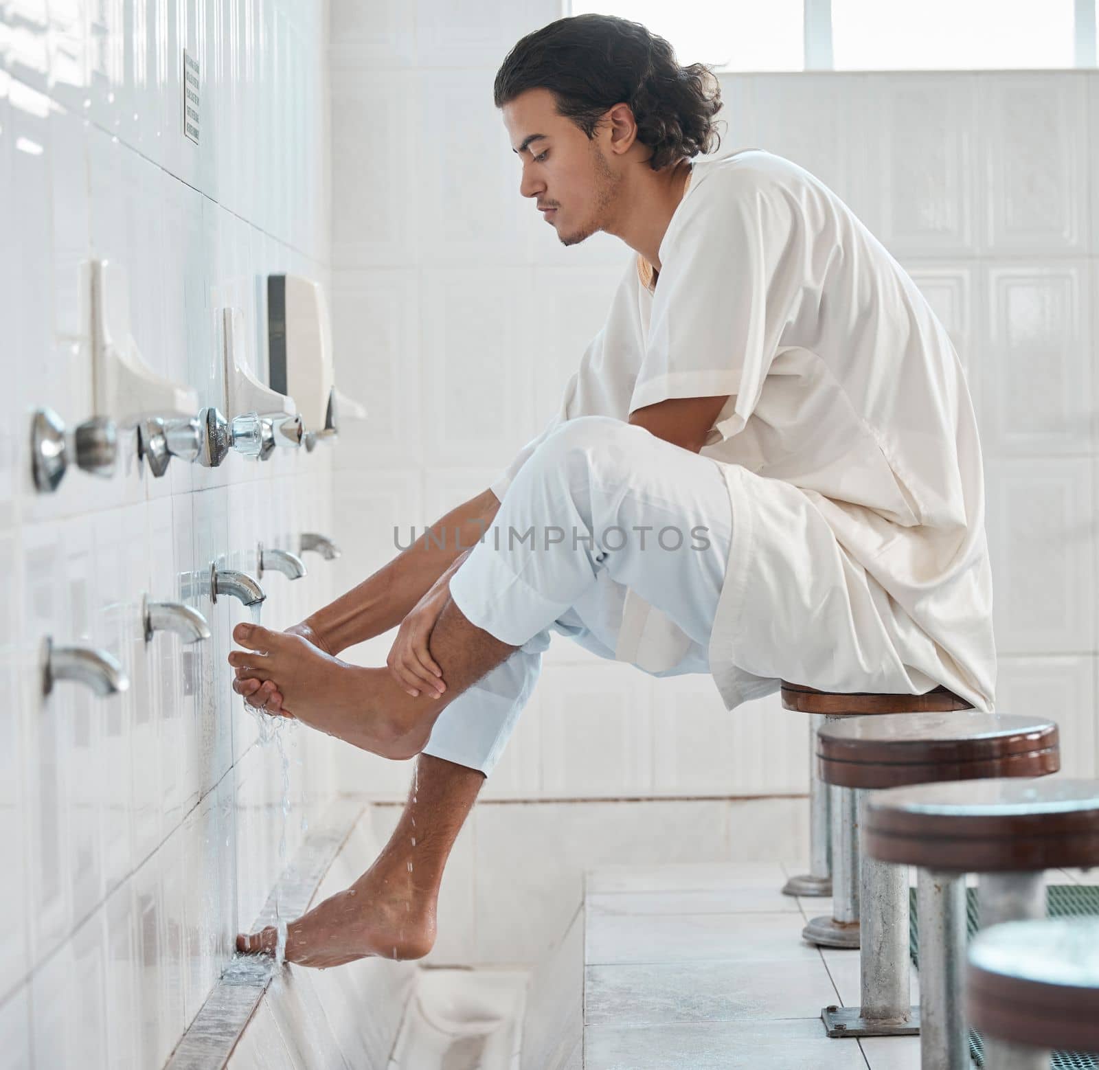 Muslim, water and man cleaning feet for ablution, wudu or spiritual purification hygiene for Islamic religion, worship or moslem culture. Indonesia mosque, Islam faith and profile of man washing foot by YuriArcurs