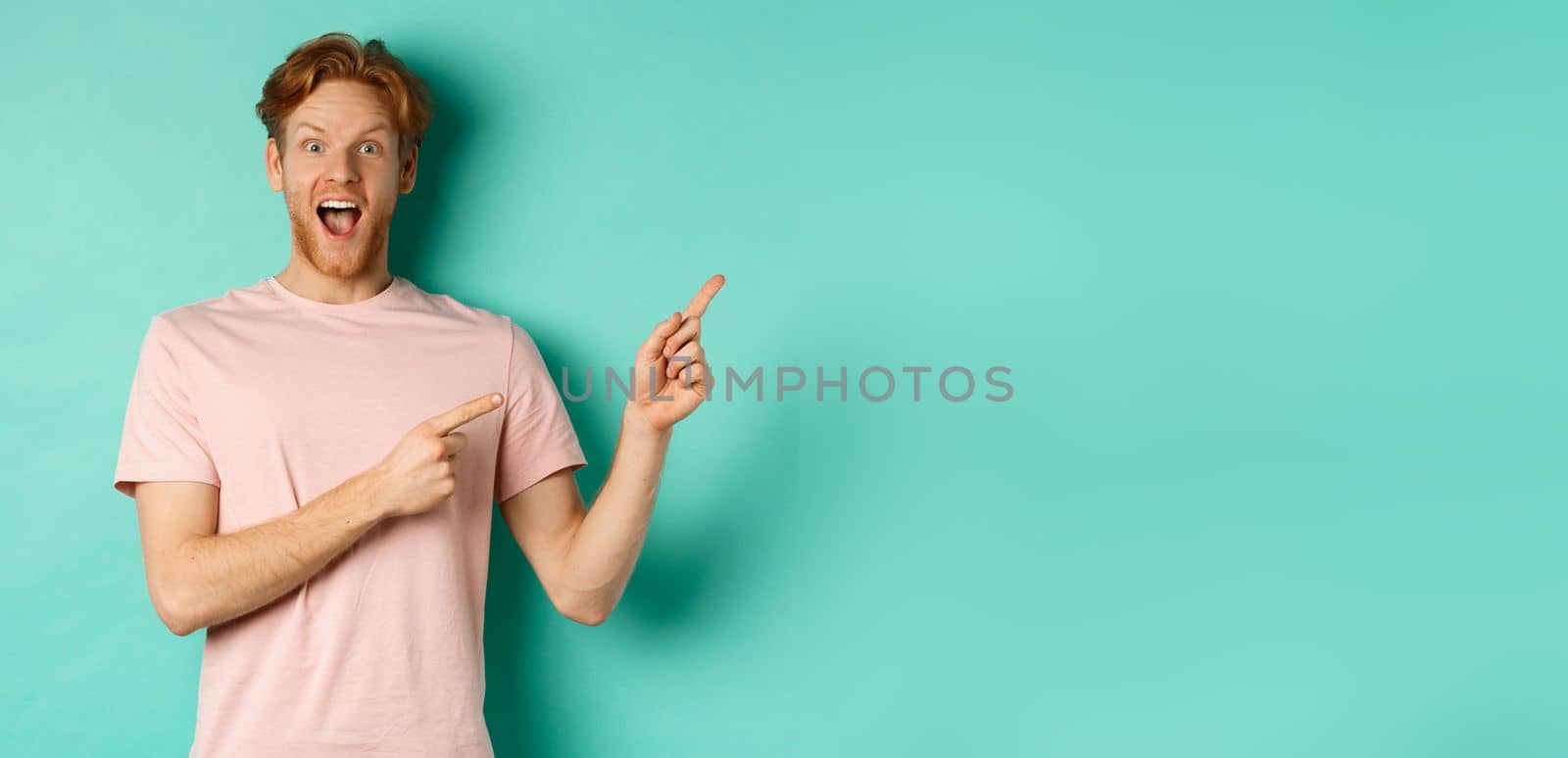 Excited guy in pink t-shirt showing advertisement on mint background, looking amazed at camera and pointing at upper right corner by Benzoix