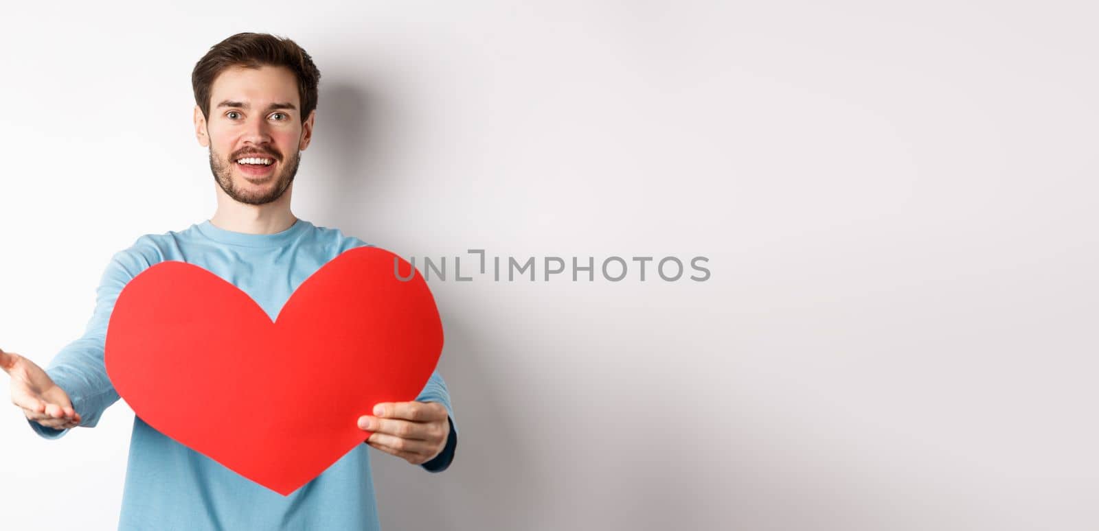 Handsome man in love making confession to you, pointing hand at camera, holding big red heart cutout on valentines day, singing romantic serenade, standing over white background by Benzoix