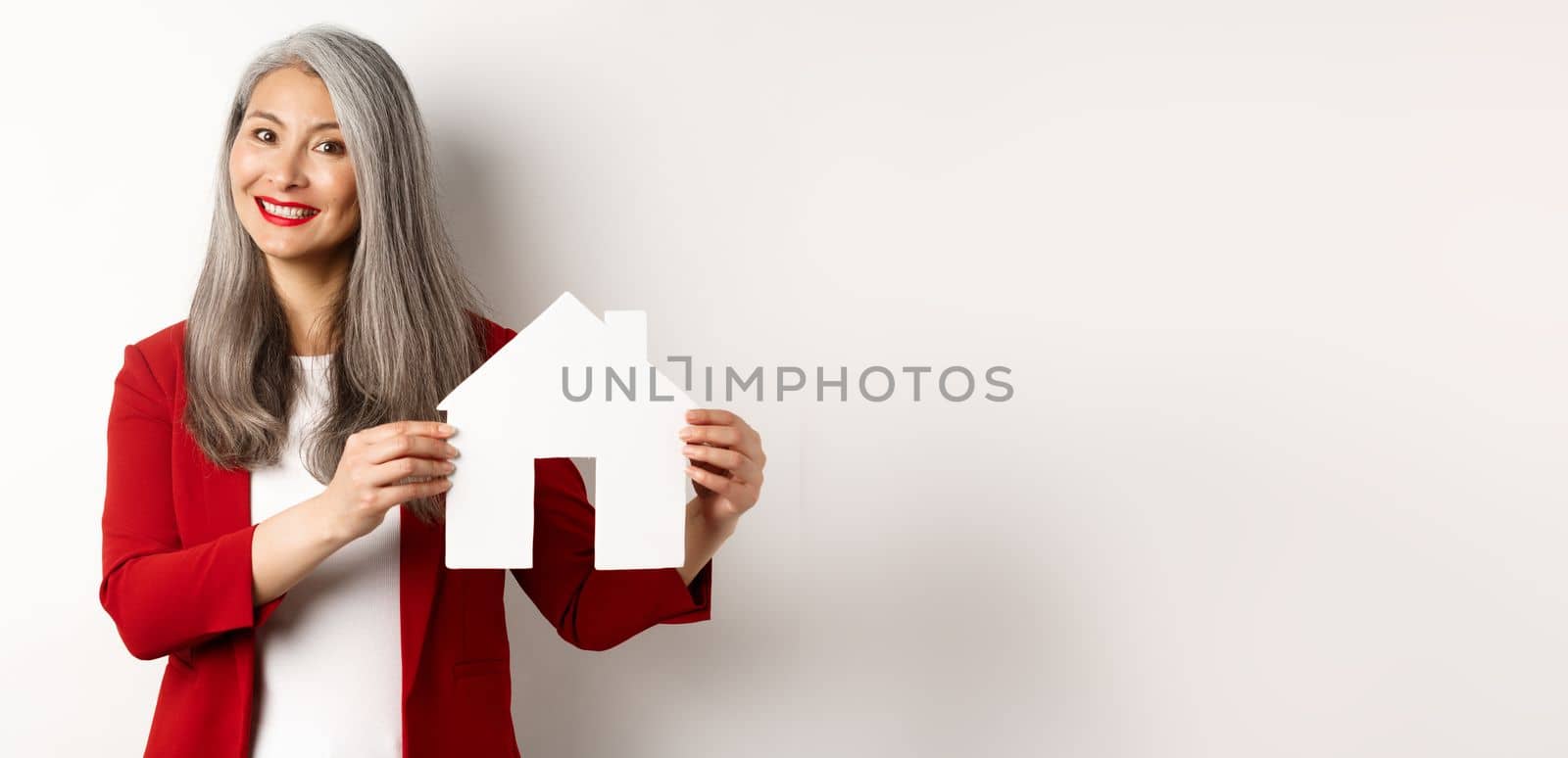 Smiling real estate agent showing paper house clipboard, broker working with client, standing over white background by Benzoix