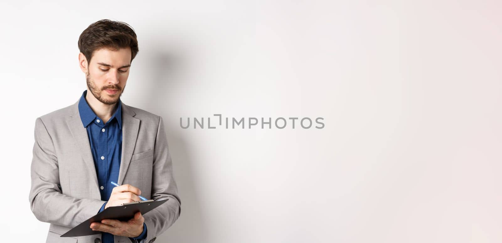 Office worker in suit writing on clipboard, taking notes on meeting, standing on white background.