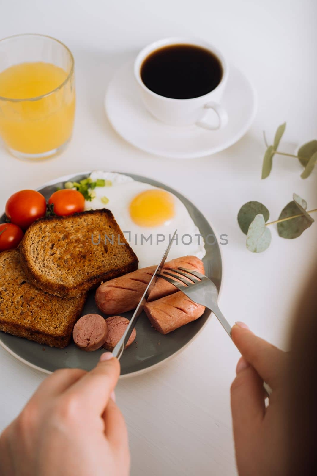 English breakfast with black coffee and orange juice, grilled sausage and whole wheat toast with fried egg and cherry tomatoes on plate