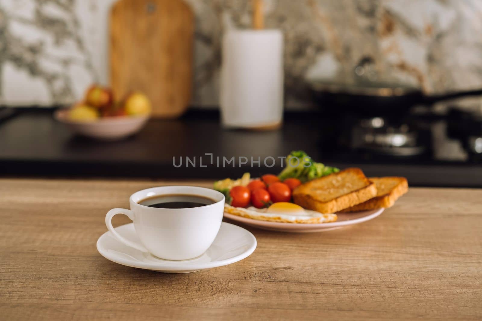 Cup of black coffee and breakfast in background in the kitchen at home