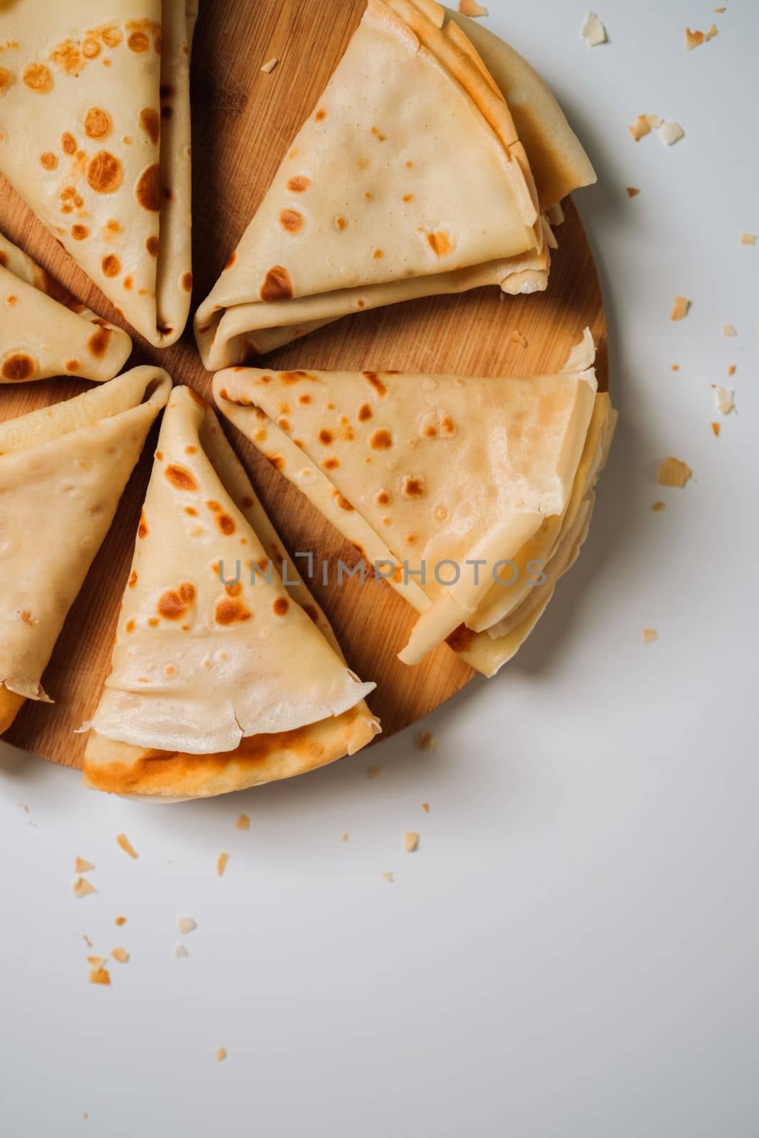 Delicious crepes laid out in triangles in a circle on wooden board, flat lay. High quality photo