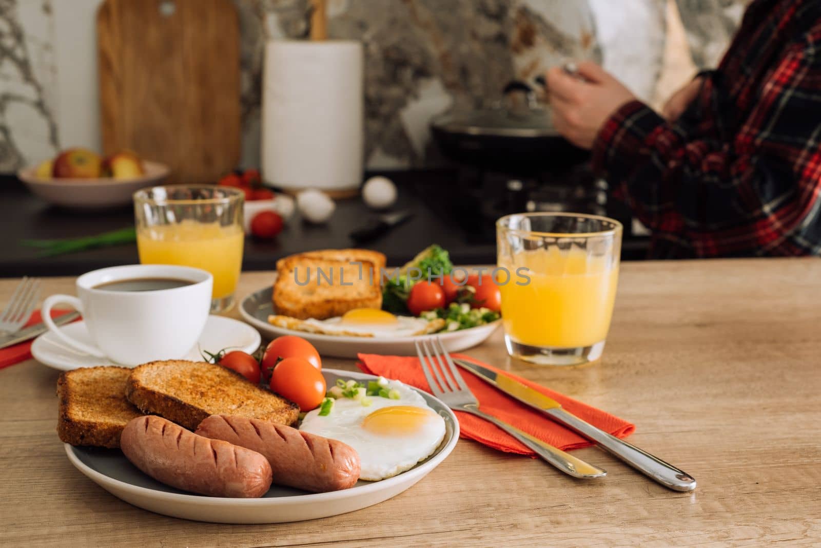 Grilled sausage with toast and fried egg, home cooked English breakfast with cup of black coffee and orange juice in kitchen