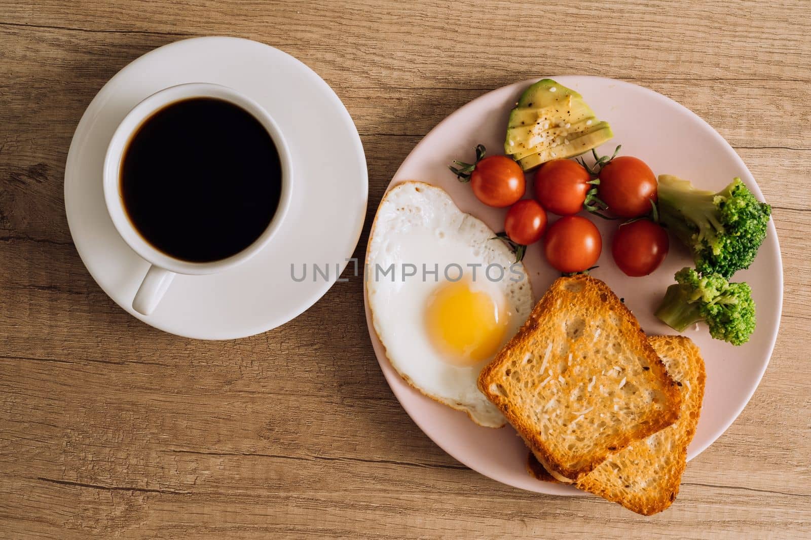 Flat lay homemade breakfast with cup of black coffee, fried egg and toast with tomatoes and avocado on plate