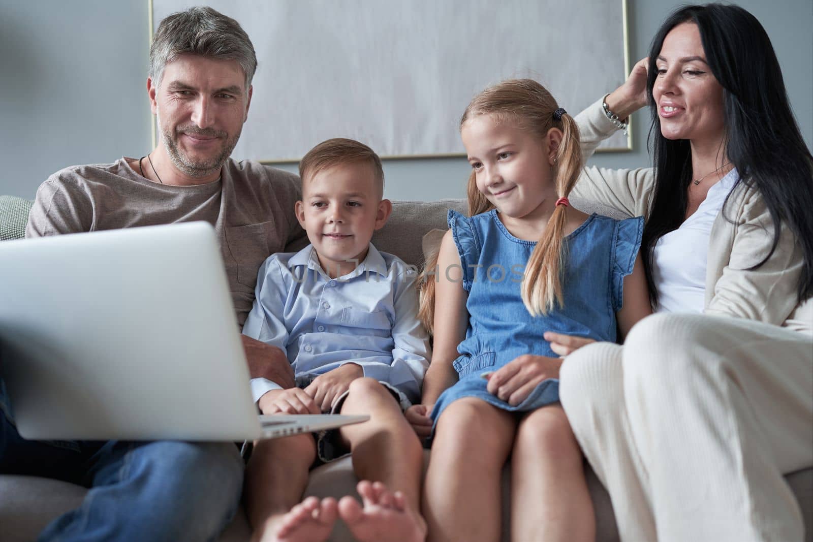 parents and their little kids using laptop at home together