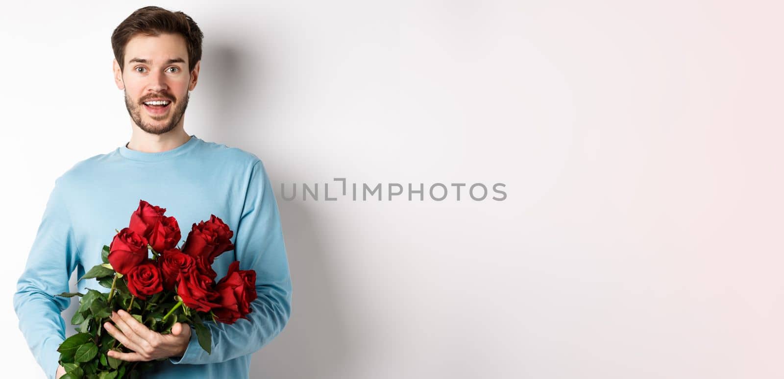 Romantic boyfriend bring beautiful bouquet of red roses on valentines day, having date with girlfriend, saying I love you, standing passionate on white background.