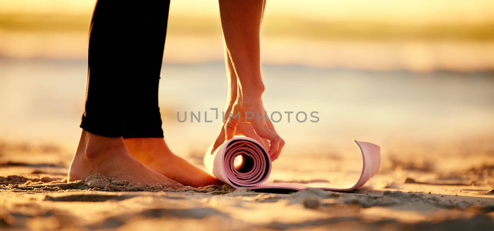 Hands, beach and woman roll yoga mat to start workout, exercise or stretching. Zen, meditation and feet of female yogi outdoors on seashore while preparing for chakra training, exercising and pilates.