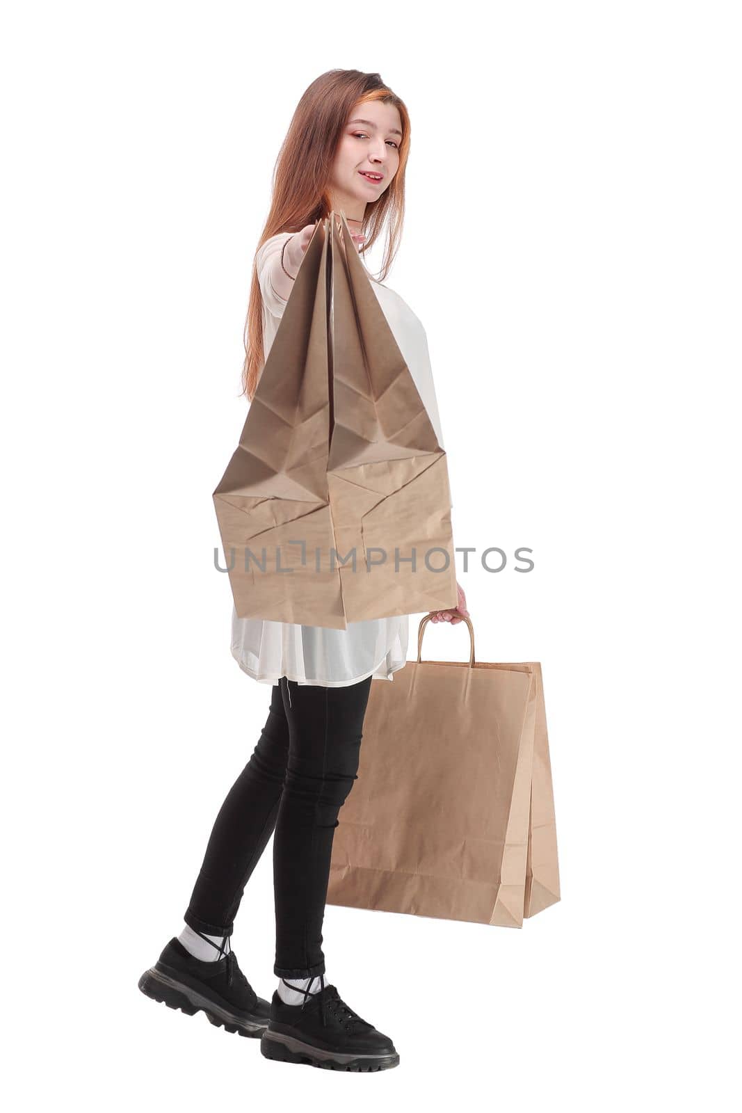 Studio photo of pretty woman walking, carrying paper shopping bags. White background.